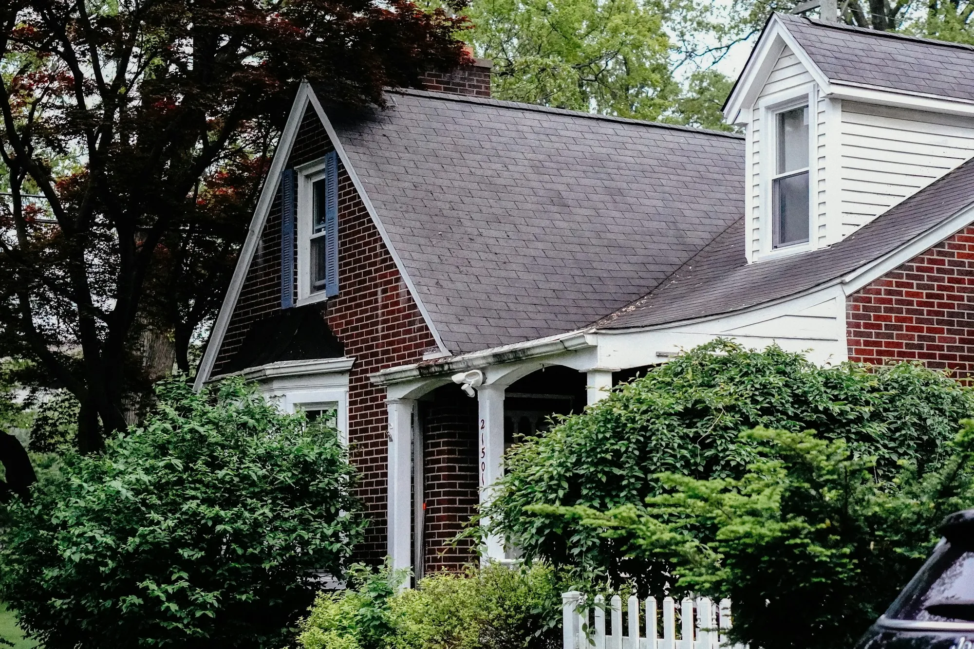 Brick cottage with a gray shingle roof and gabled entry