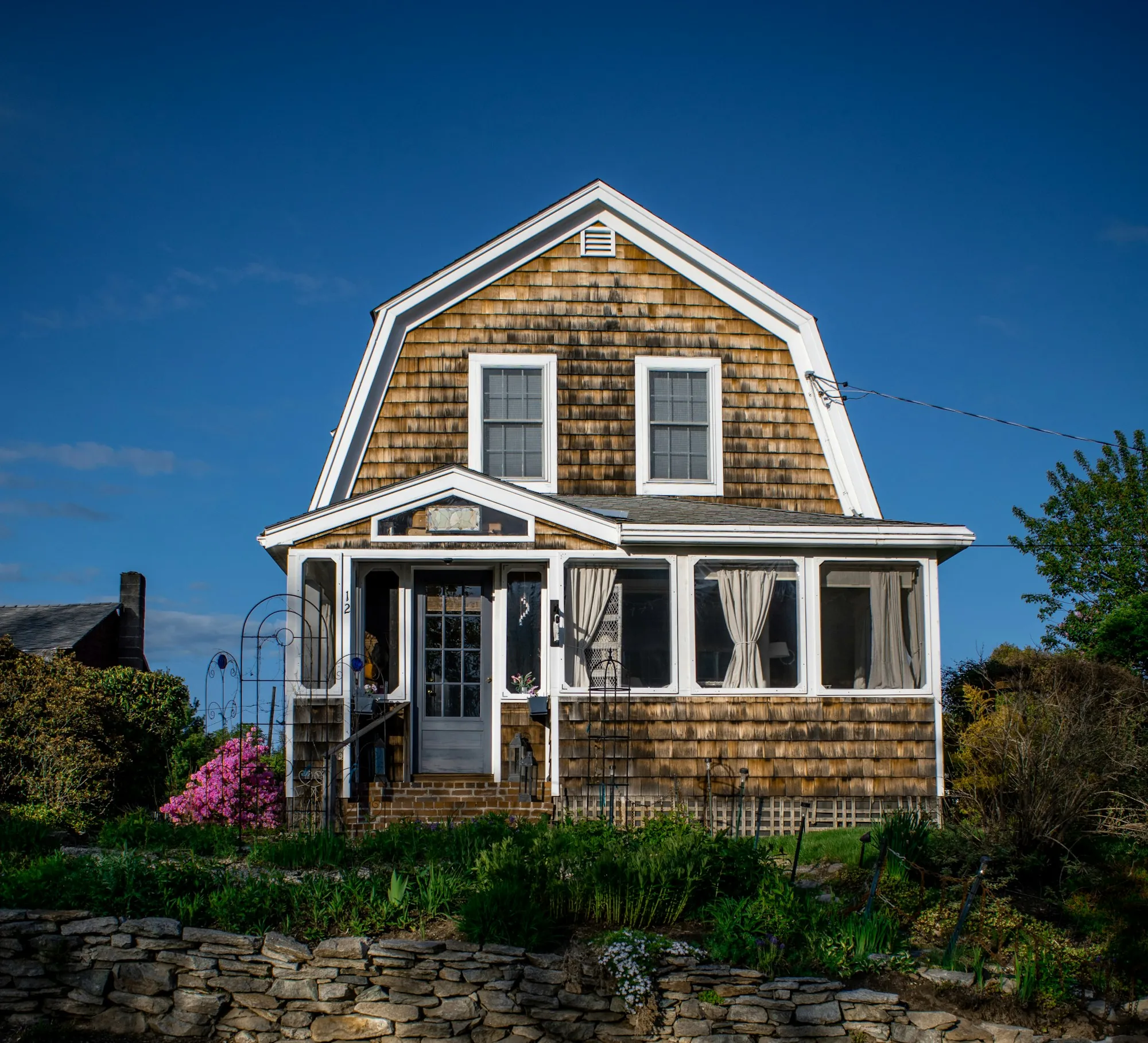 Dutch colonial home with a gambrel shingle roof and shingle siding