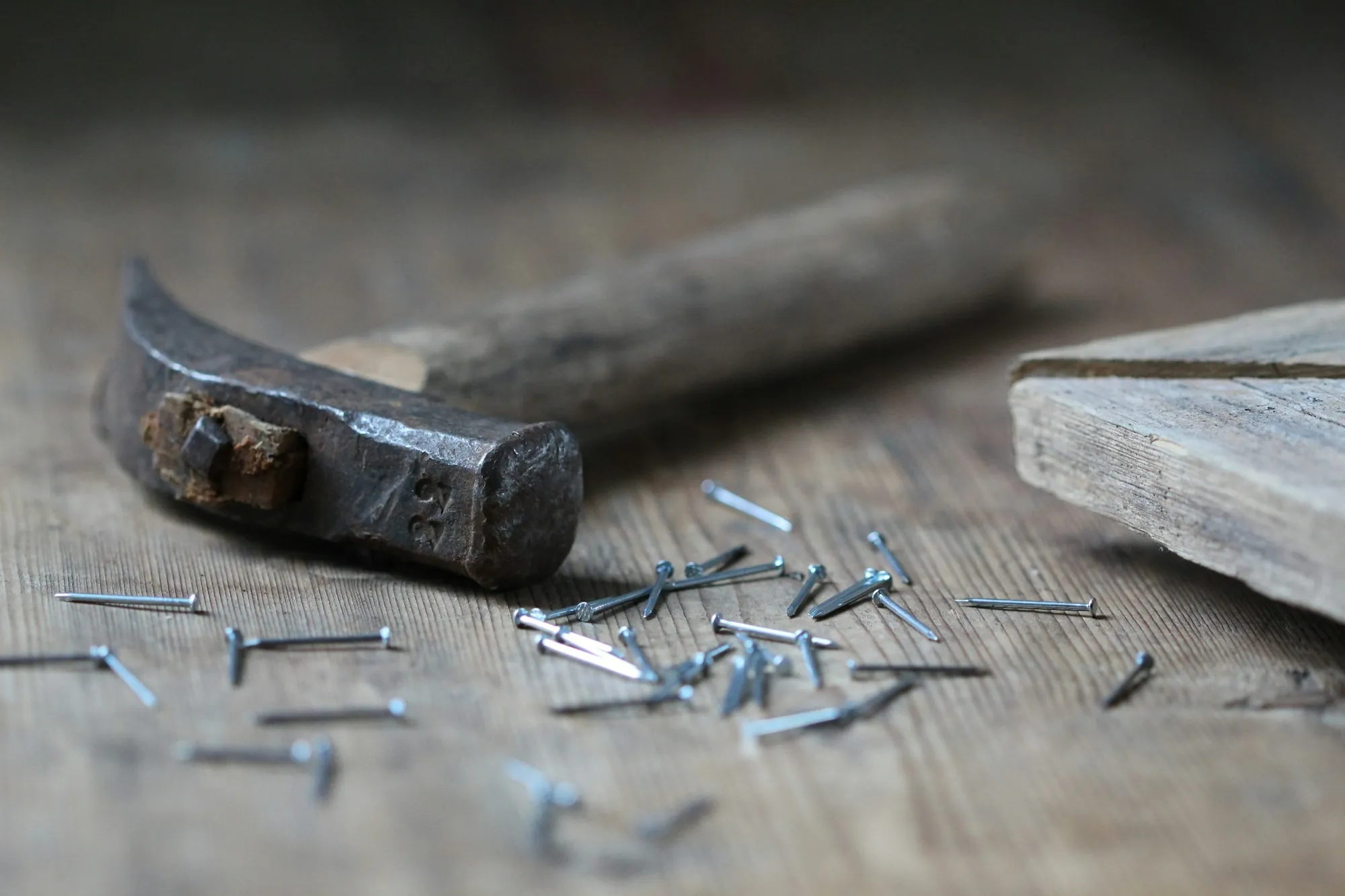 Hammer and scattered nails on a weathered wood board
